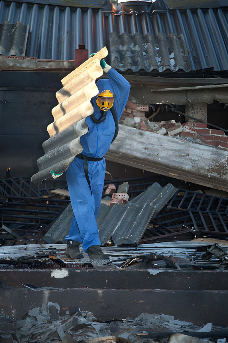 Geschützte Fachkraft beim kontrollierten Rückbau von Asbestzement-Wellplatten