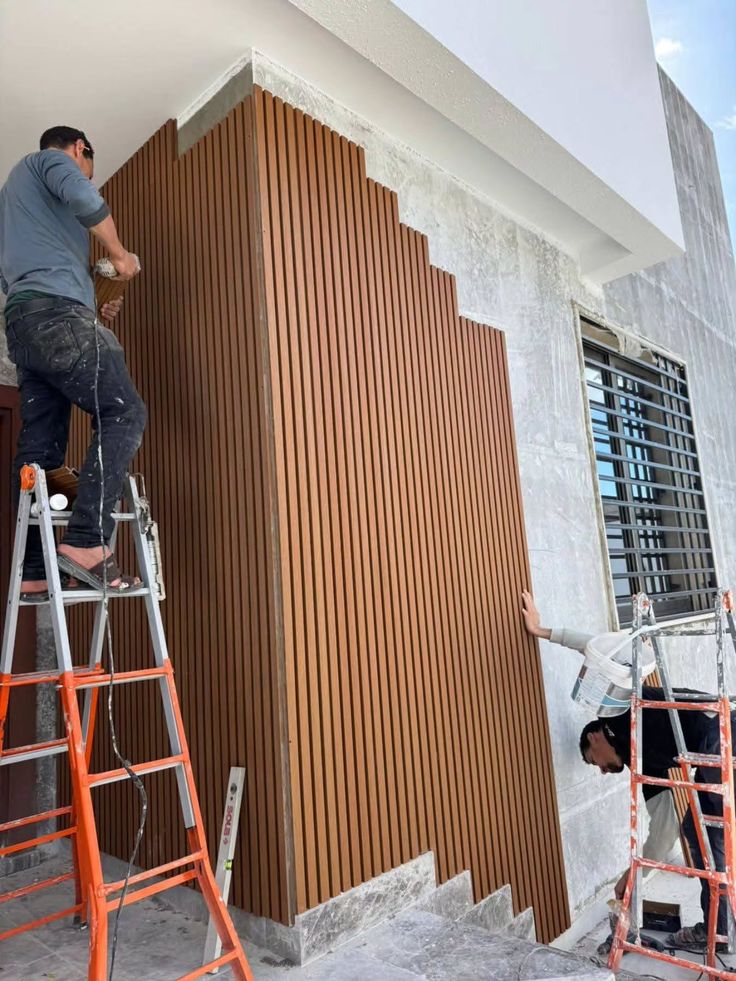 Handwerker bei der Montage einer dekorativen Fassadenverkleidung in Holzoptik